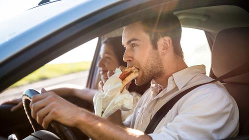 Man eating hamburger in car